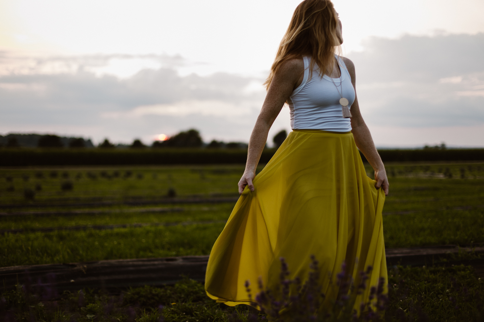 Red headed woman in yellow skirt at sunset in a lavender field.